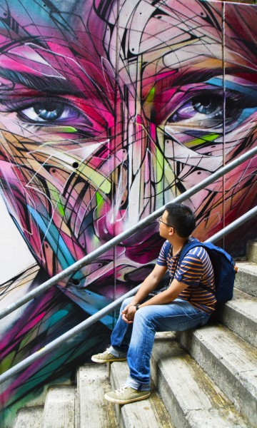 I Tank Lane, har gatekunstnere dekorert veggene. Owen Kam (33) lar seg imponere. Foto: Mari Bareksten 