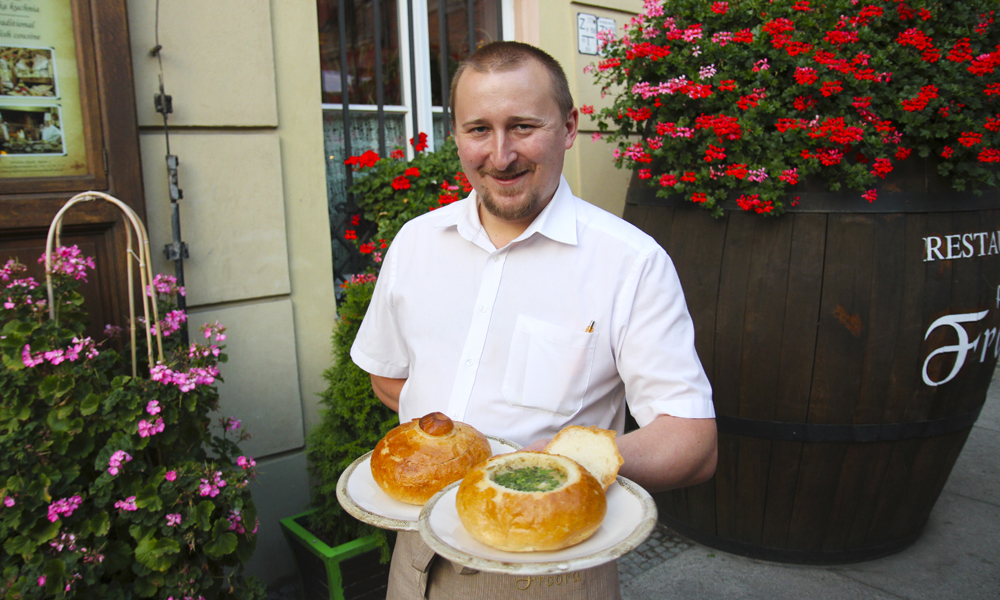 Tomasz Wyskoczyl (28) serverer tradisjonell zurek i brød på restaurant Pod Freda midr på den historiske handelsplassen. Foto: Runar Larsen