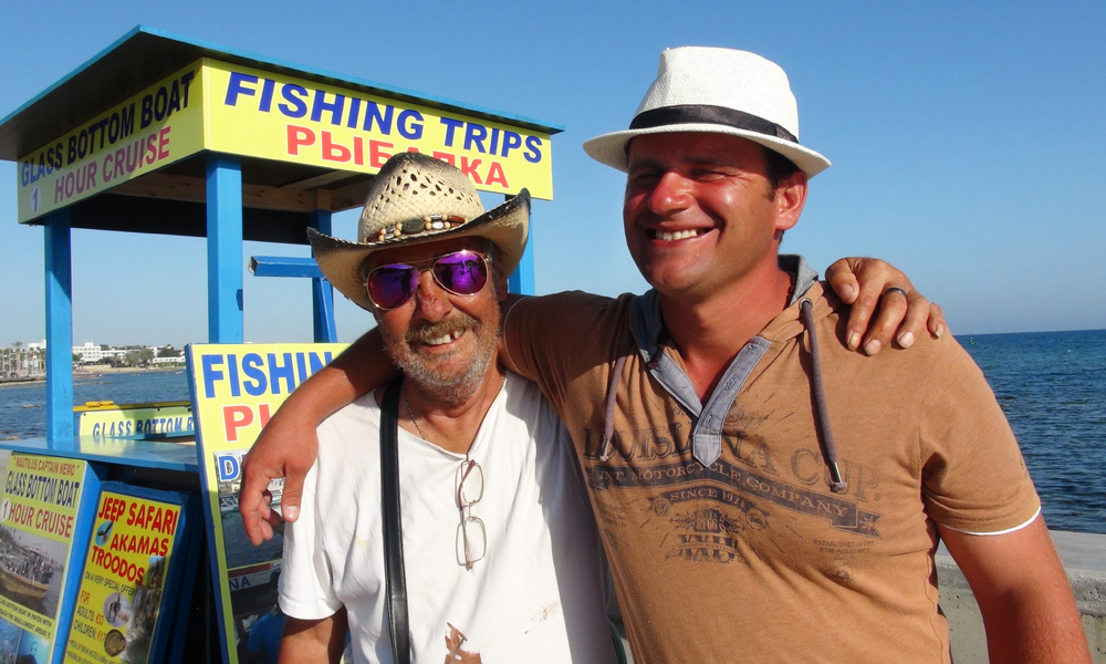 Fisketurer, dagscruise, jeepsafari – det er nok å gjøre. Andy Pearson (63) og Michail Todorov (57) anbefaler tur med fiskebåt fra havna i Pafos. Kanskje ikke så rart – de selger dem. Foto: Torild Moland 