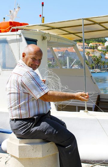 Langs havnen sitter lokale fiskere og drar inn storfangst. Foto: Ida Anett Danielsen 