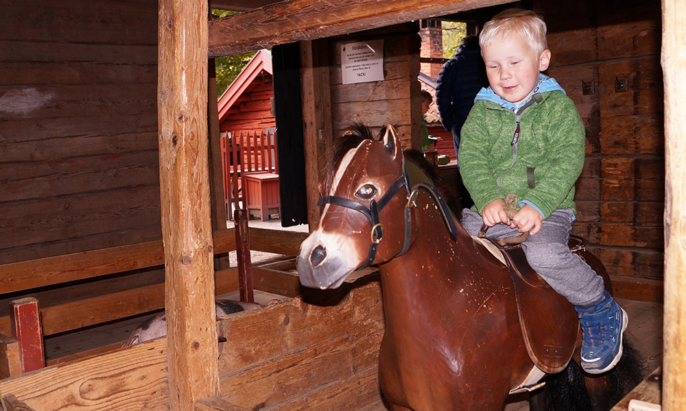 Her prøver Fillip August (3) å ri på hesten på lekebondegården. Foto: Trude Grande Fjellbirkeland