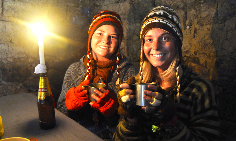 Mia K. Kalleberg og Ingrid får i seg varmen i en hytte de låner langs veien for å søke ly for regnet. Foto: Ingrid Holtan Søbstad