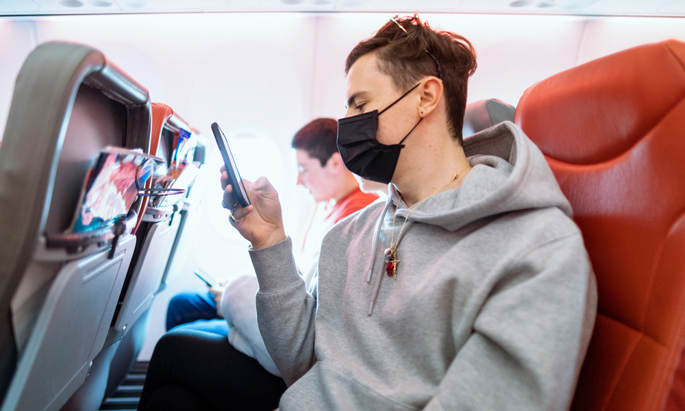 Folk på fly med smittemaske