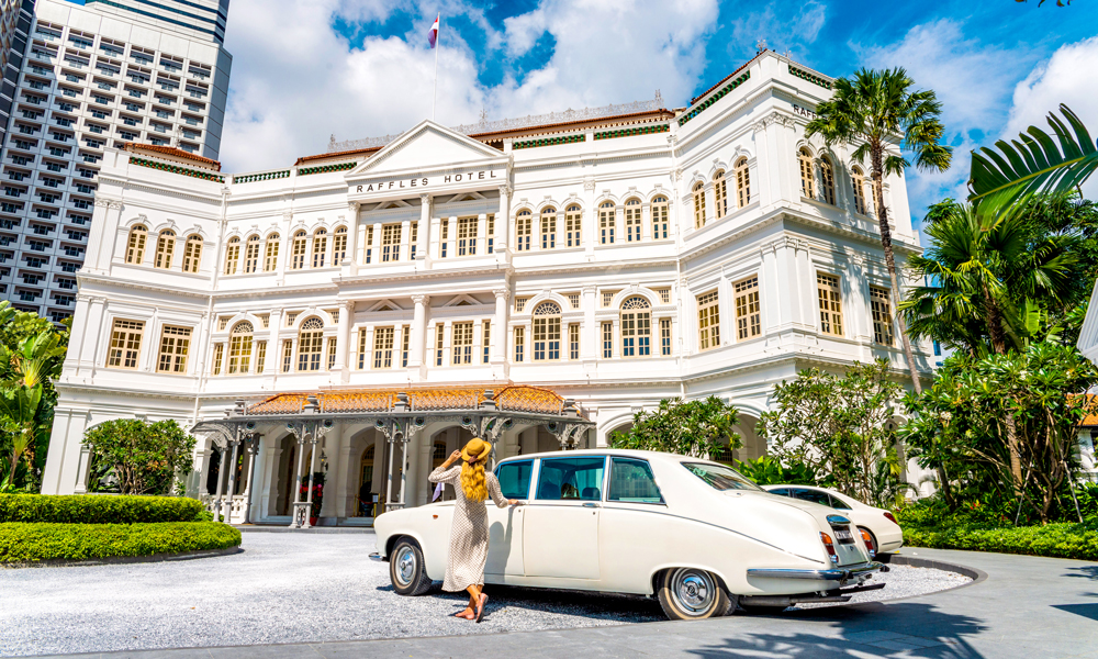 Nyvasket hvit vintage Daimler Limousine står parkert utenfor det herskapelige hotellet Singapore Raffles.